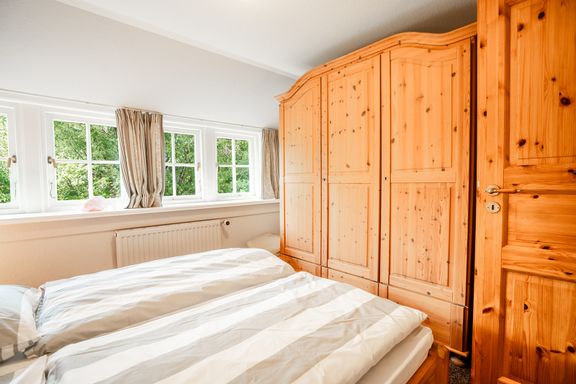 Im Schlafzimmer mit Doppelbett steht ein Kleiderschrank
