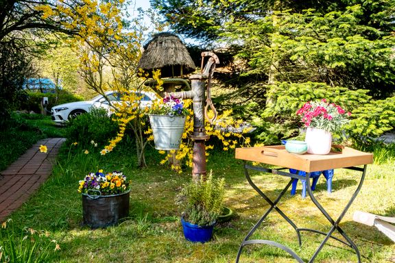 liebevoll dekorierter Garten und Weg zum Parkplatz mit E-Ladesäule
