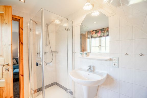 Im Badezimmer mit Waschbecken und Spiegel und Dusche 