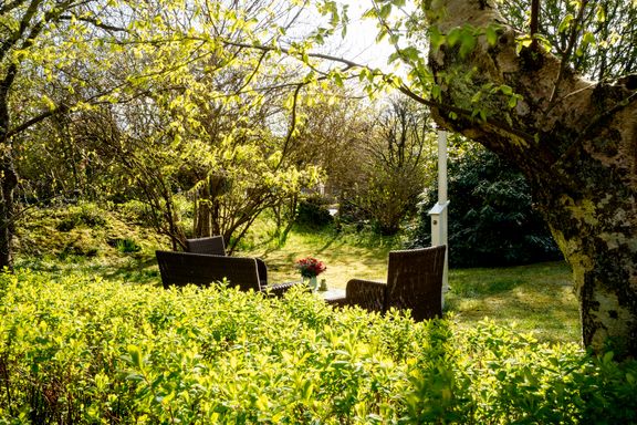 Loungemöbel im Sonnenschein im grünbewachsenen Garten von Haus Margarete