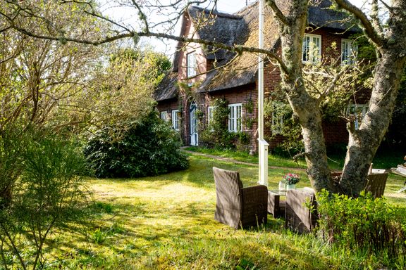 Das reetgedeckte Friesenhaus Margarete ist von einem liebevoll gepflegten Garten umgeben, wo sich Loungemöbel befinden