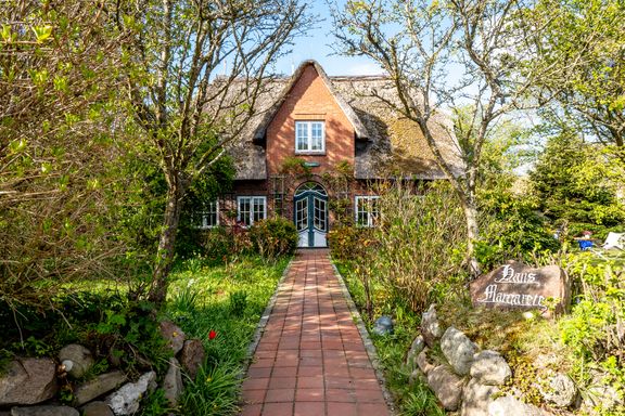 Grün bewachsener Weg führt zum Haus Margarete, welches von einem Friesenwall umfriedet ist