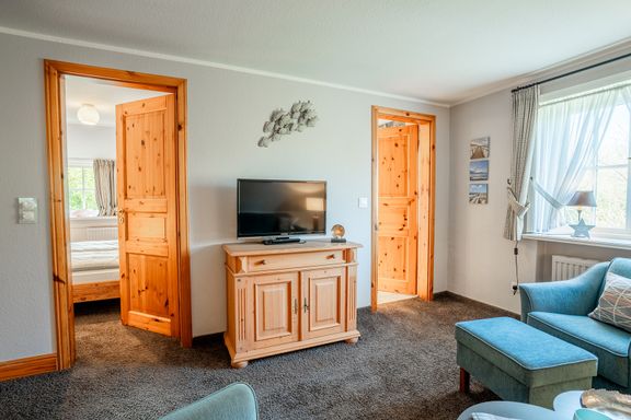 Wohnzimmer im Haus Margarete mit Blick auf TV und Türen zu Schlafzimmer und Bad
