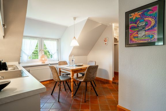 In der Küche steht am Fenster ein Holztisch mit vier Stühlen