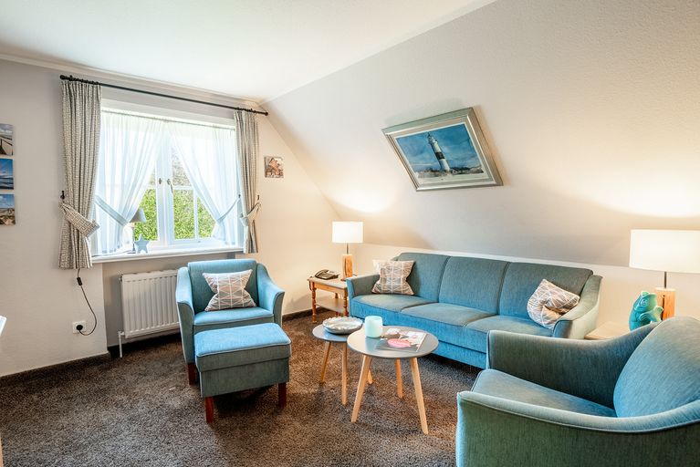 Im Wohnzimmer steht ein Sofa mit zwei Sessel in Fensternähe