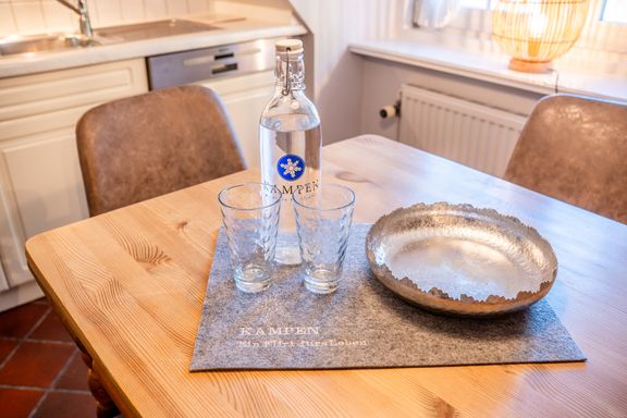 Auf dem Küchentisch stehen eine Glasflasche von Kampen und zwei Gläser und daneben eine Dekoschale